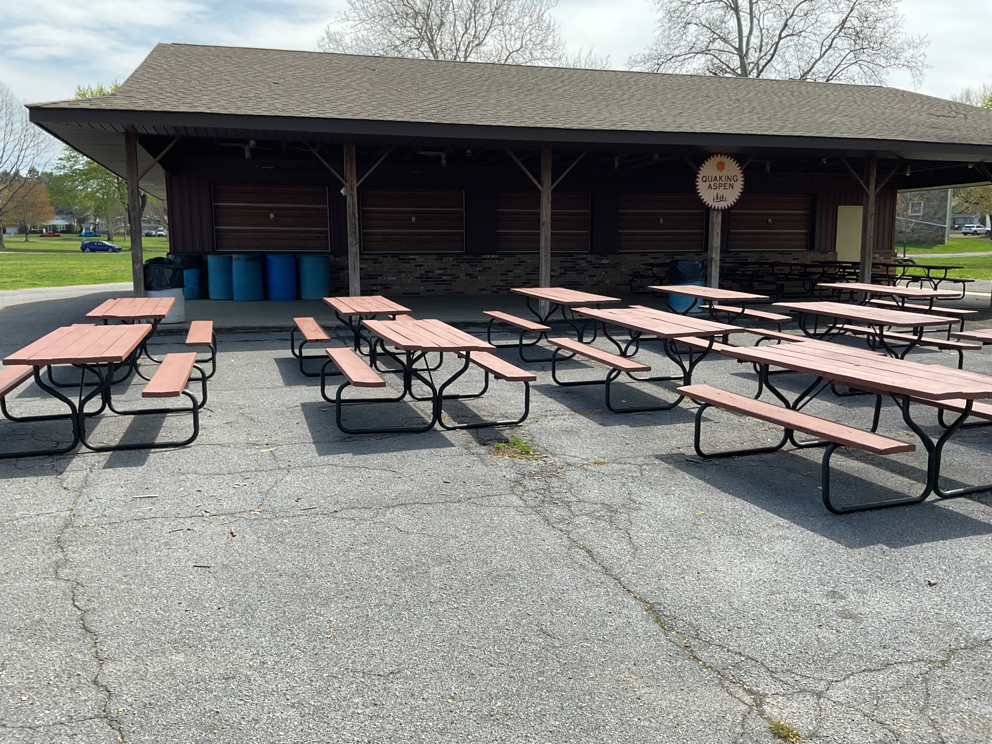 Building with an overhang with three rows of picnic tables in front of it.
